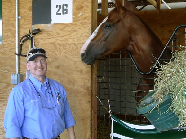 Reverend Bunker standing outside a barn with a horse