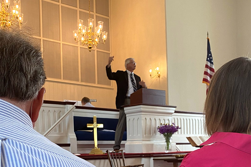 Pastor John inside church giving sermon at Sunday worship