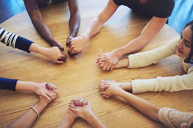 Photo of diverse people holding hands in prayer