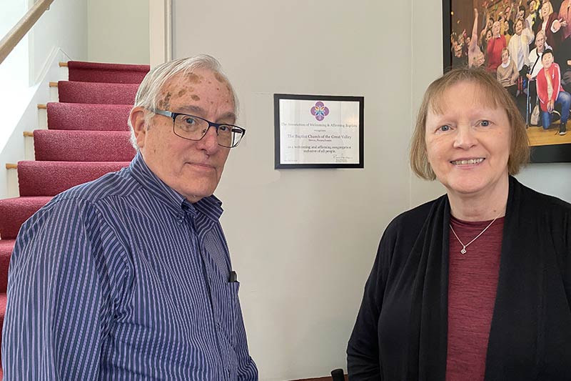 Photo of Mary Ann Robinson, Church Clerk, and Tom Winters, Church Moderator hanging the AWAB certificate in the vestibule of the Meeting House