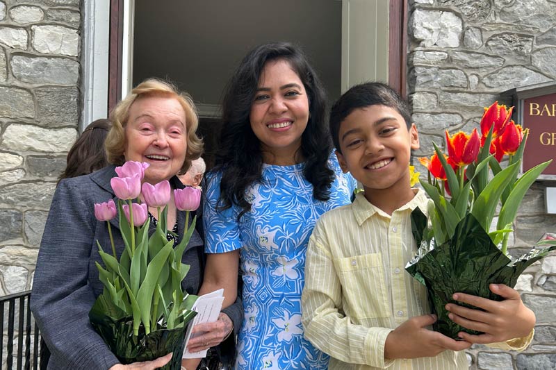 Photo of church members holding up flowers in front of the church entrance