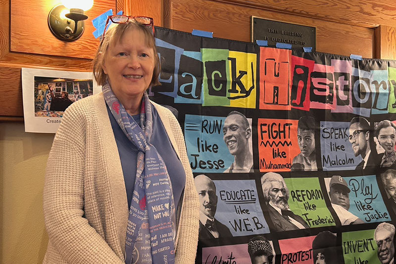 Photo of a woman standing beside a Black History display