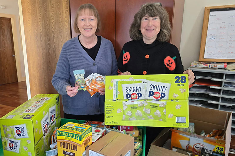 Photo of two women holding up donated snacks